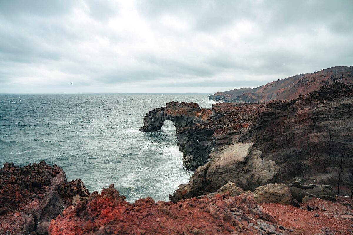 Rugged sea cliff edges and rock formations in red rock and old lava on Westman islands.