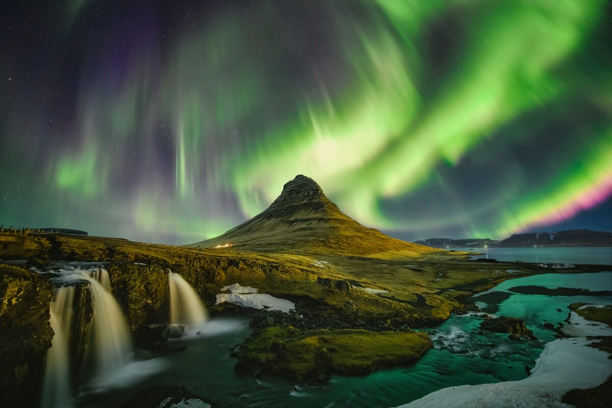 Kirkjufell mountain and waterfalls during northern lights in winter,