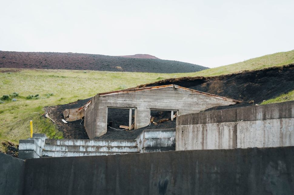 Ruins of a house partially buried in volcanic ash and lava on Heimaey Island, remnants of the 1973 Eldfell eruption.