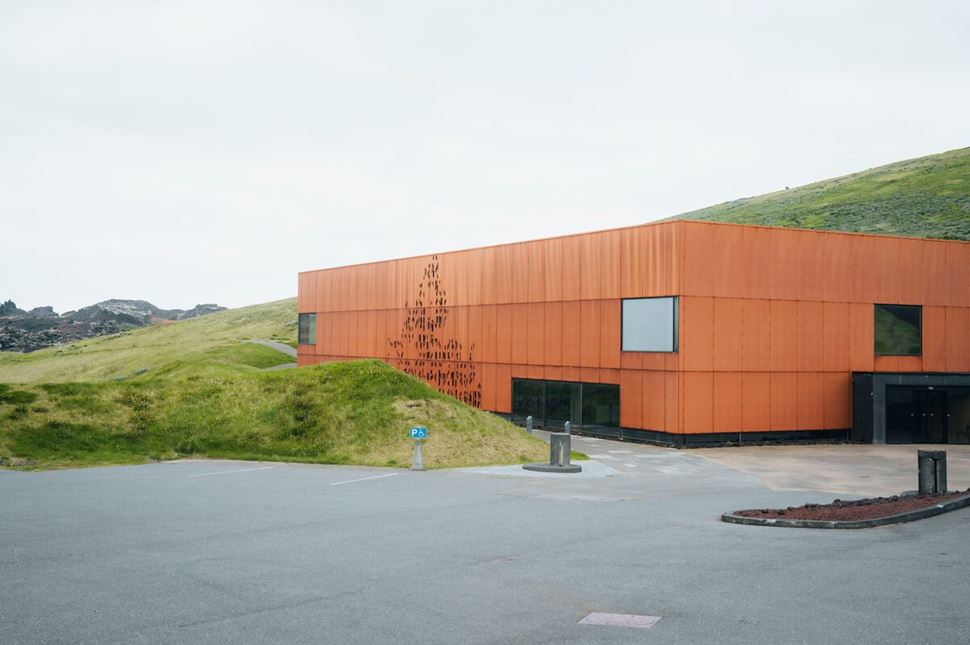 Modern rust-colored building of the Eldheimar Museum, set against the rugged volcanic landscape of Heimaey.