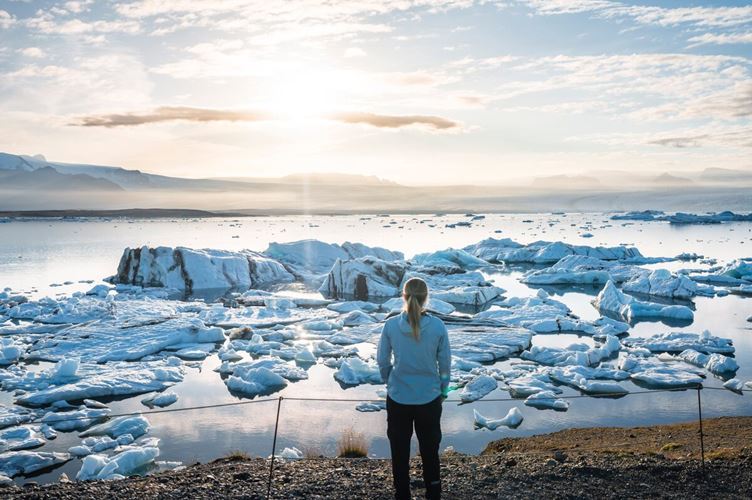 Lady standing at viewpoint at the Jokulsarlon glacier lagoon during early sunset.