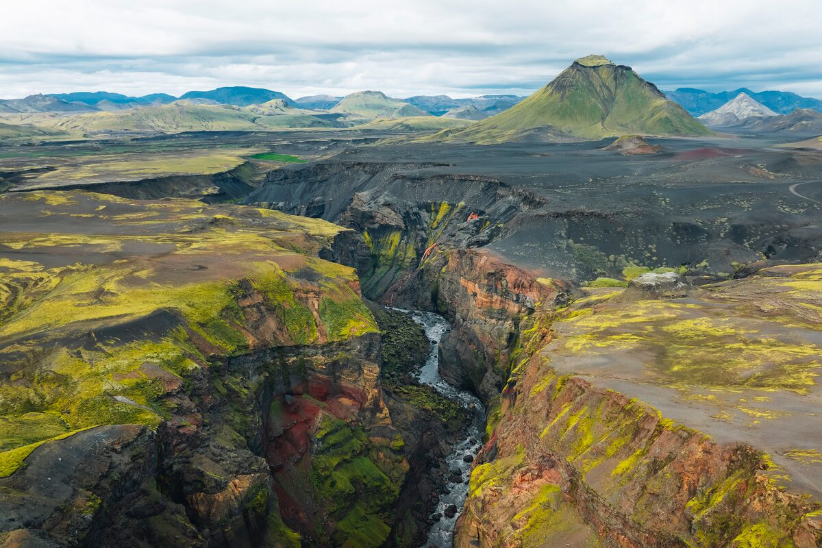 Colorful rugged landscape with stream running in between mountains at Laugavegur, in the Icelandic highlands during summer.