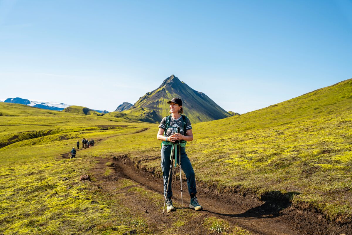 Female hiker posing for photo on Laugavegur hiking route in lushious green mountain landscape, summer.