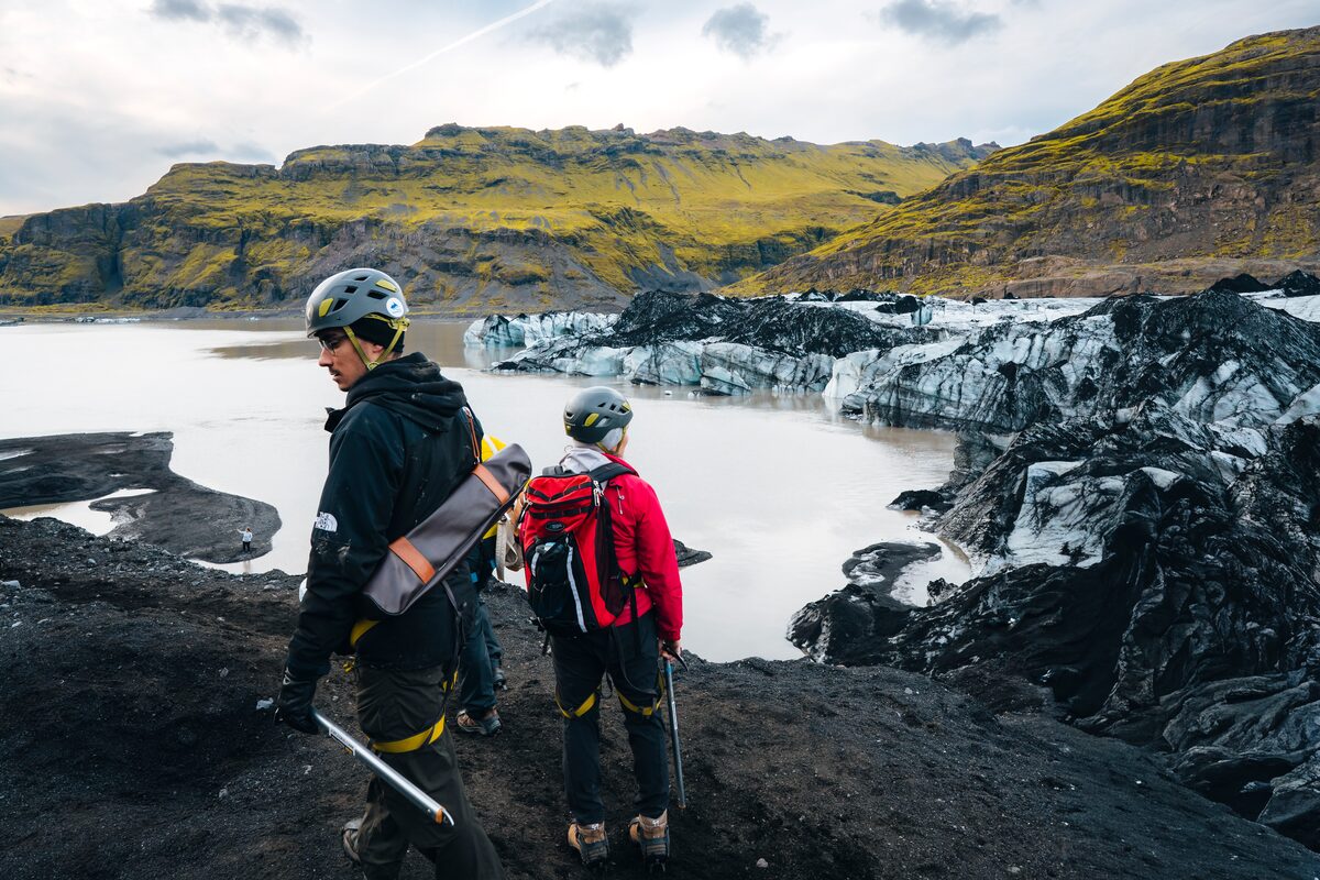 Two tourists standing on Solheimajokull glacier looking at the black and white glacier patterns.
