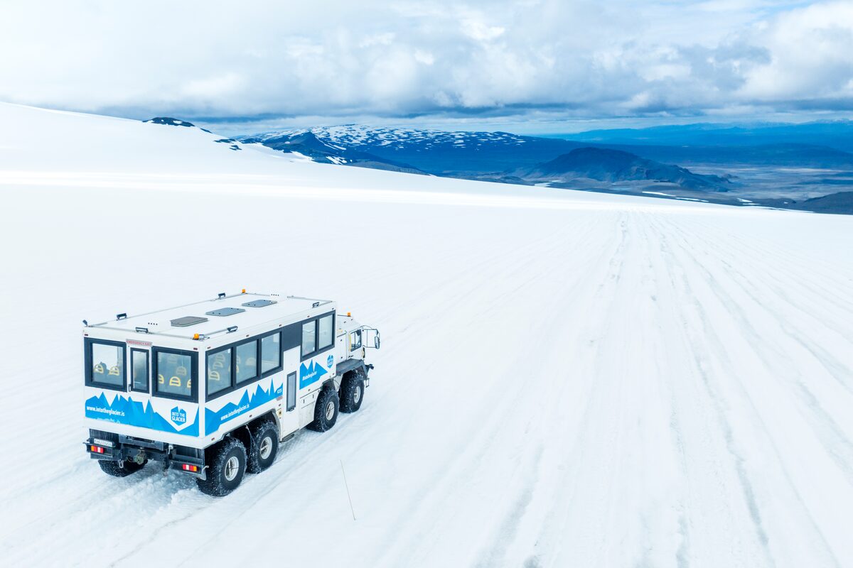 Into the glacier monster truck driving across Langjokull glacier with views of the  cloudy horizon.