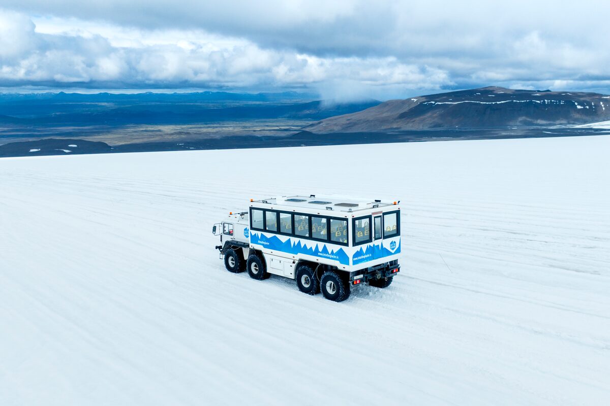 Into the glacier monster truck driving across Langjokull glacier with views of the  cloudy horizon.
