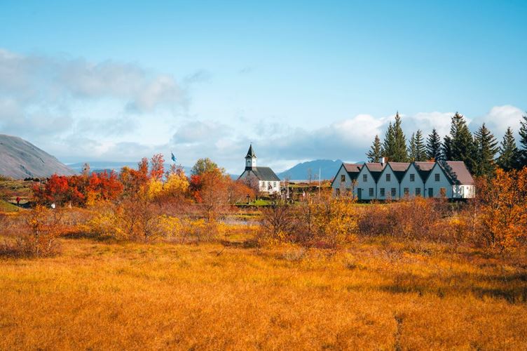 Houses at Thingvellir National park during autumn, landscape of orange and red foliage.