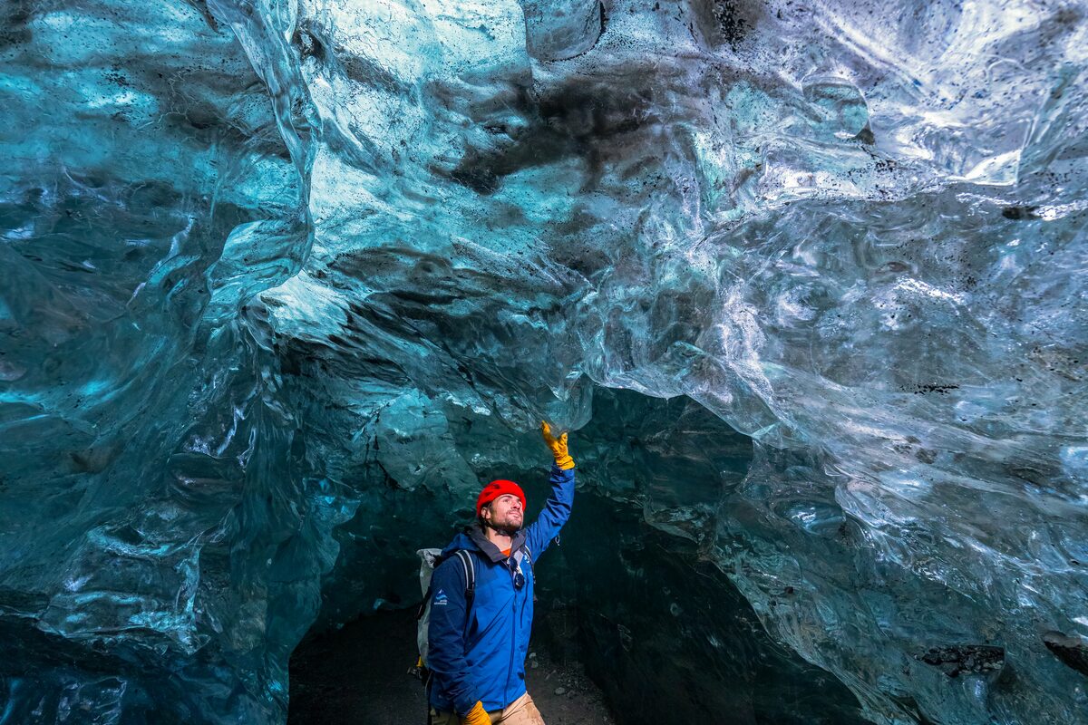 Tourist touching the blue crystal ice cave walls inside Crystal ice cave in Vatnajokull.