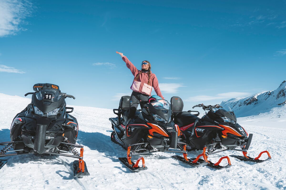 Female standing up on snowmobile, posing for photograph while on snowmobiling tour at Langjokull glacier.