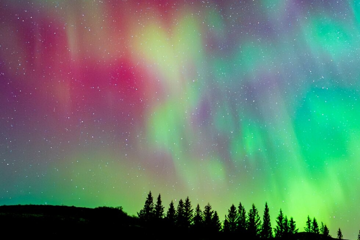 Pink, green and yellow rare colored Aurora Borealis in night sky in south west Iceland.