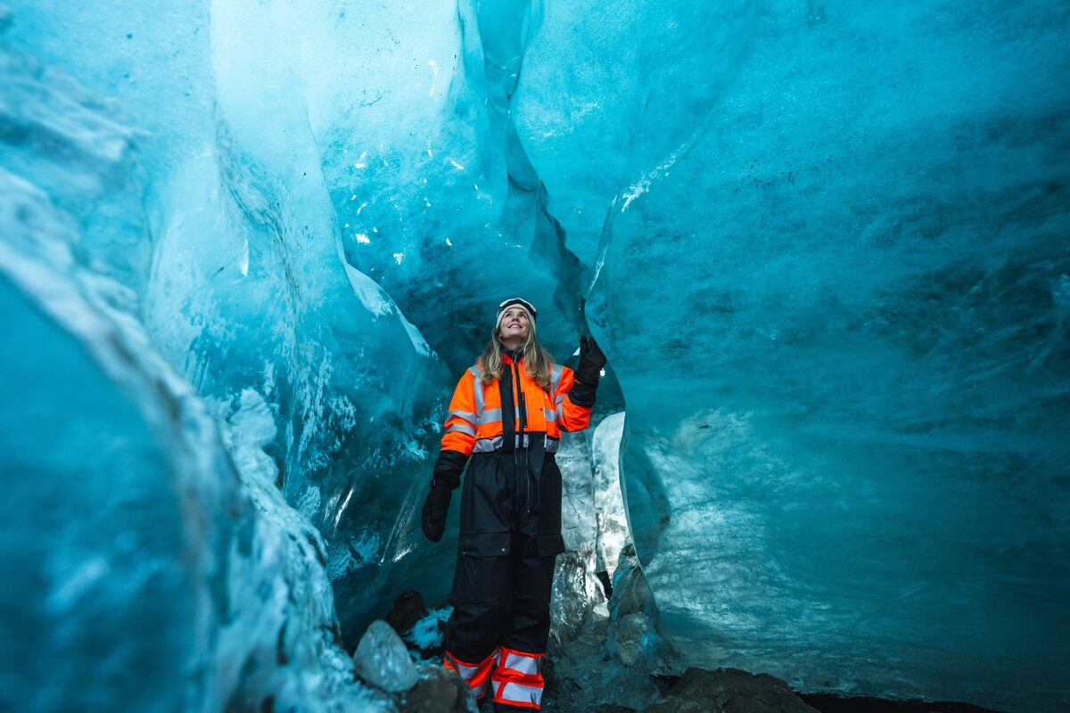 Female exploring inside brihgt blue Neptune ice cave at Langjokull glacier.