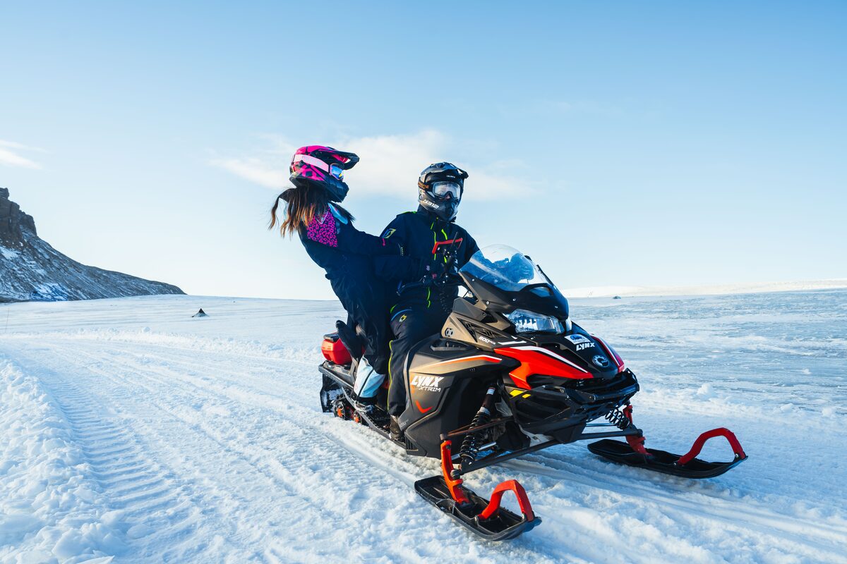 Couple sharing snowmobiling ride across Langjokull glacier.