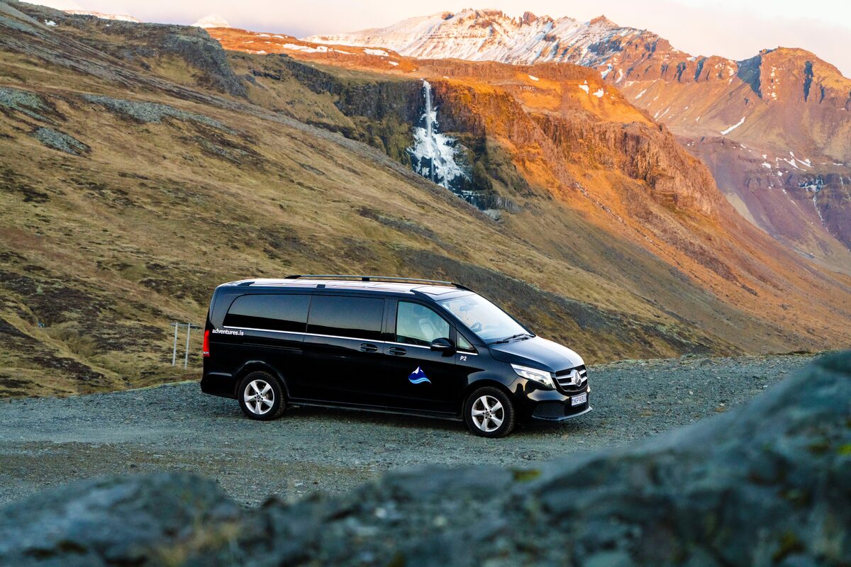 Arctic Adventures Mercedes Benz parked in front of waterfall at Snaefellsnes during sunset.