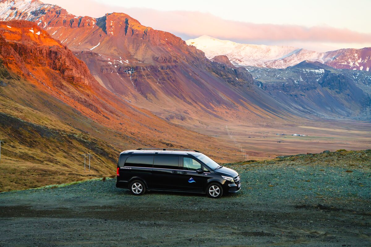 Arctic Adventures Mercedes van parked in front of Fjords in Snaefellsnes Peninsula during sunset.