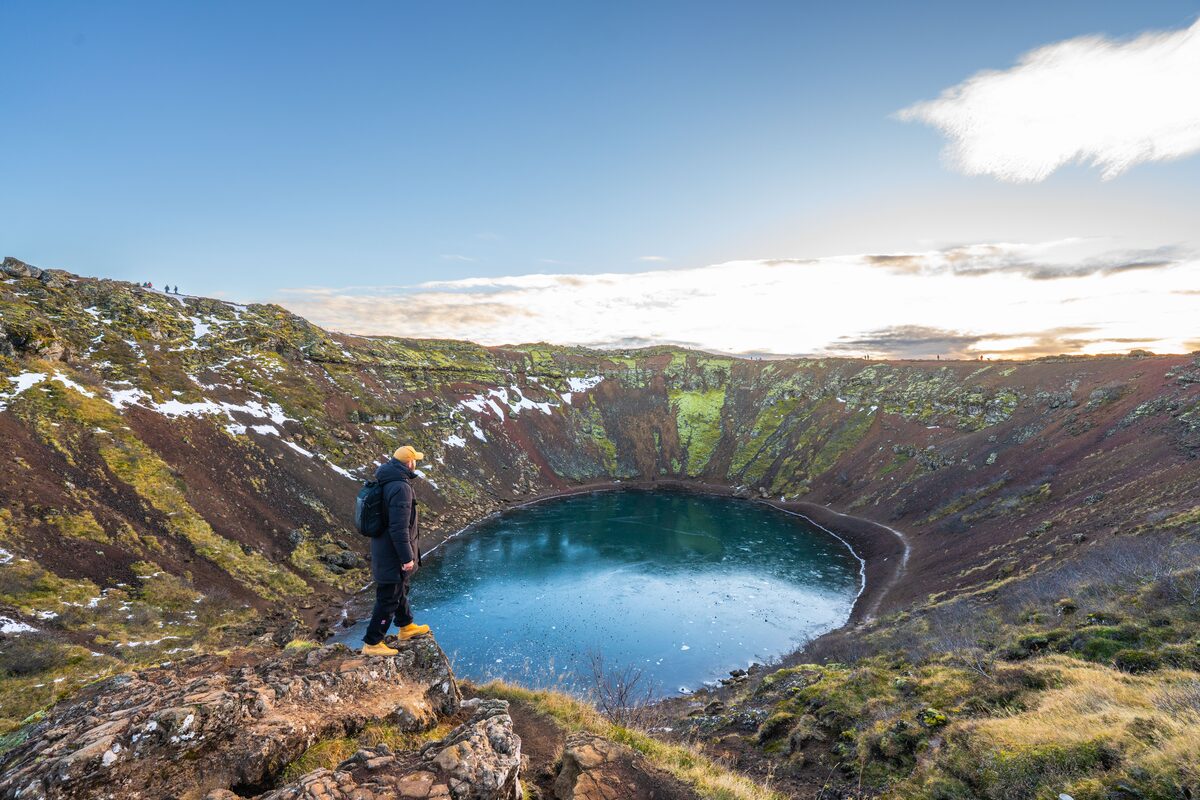 Man standing at the edge of Kerid Volcanic Crater in Iceland during winter months.