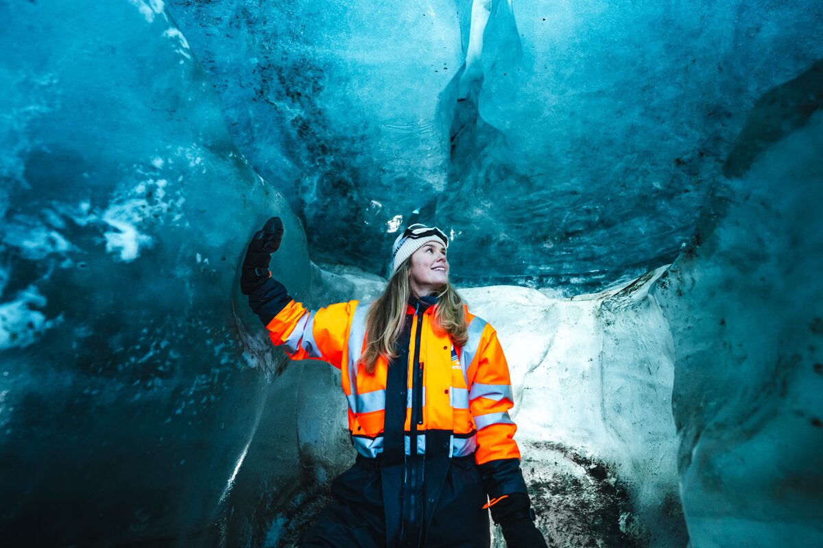 Woman In Snowmobiling Gear Touching The Walls Of An Ice Cave in Iceland