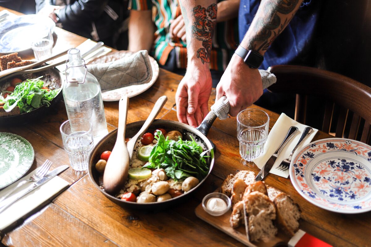 Waiter with tattooed arms serving hot Icelandic meal in restaurant in Reykjavik city.