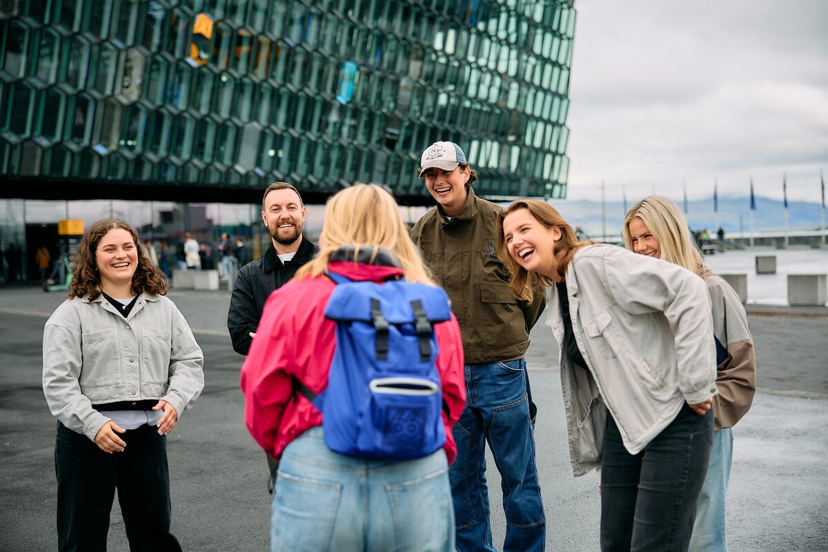 Small group of friends standing together and laughing outside the Harpa concert hall in Reykajvik.