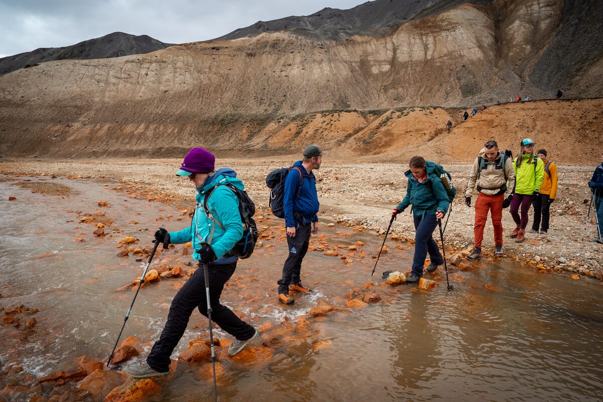 Small group of hikers hiking across a stream on the Laugavegur trail.