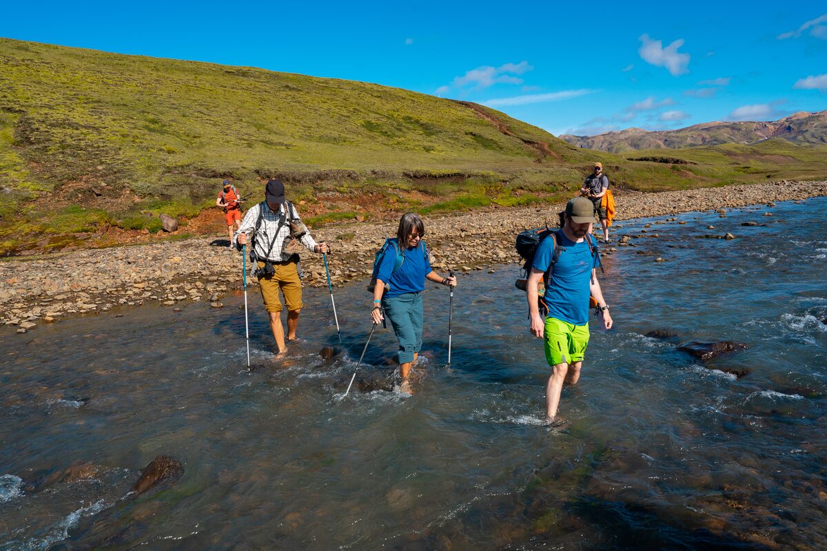 Small group of hikers crossing a stream on Laugavegur trail in Iceland.