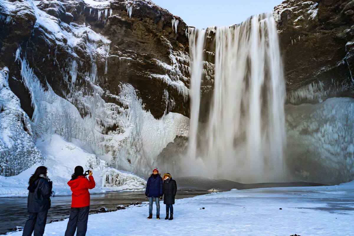 Small group exploring around at the Skogafoss waterfall in Iceland during heavy snow fall.