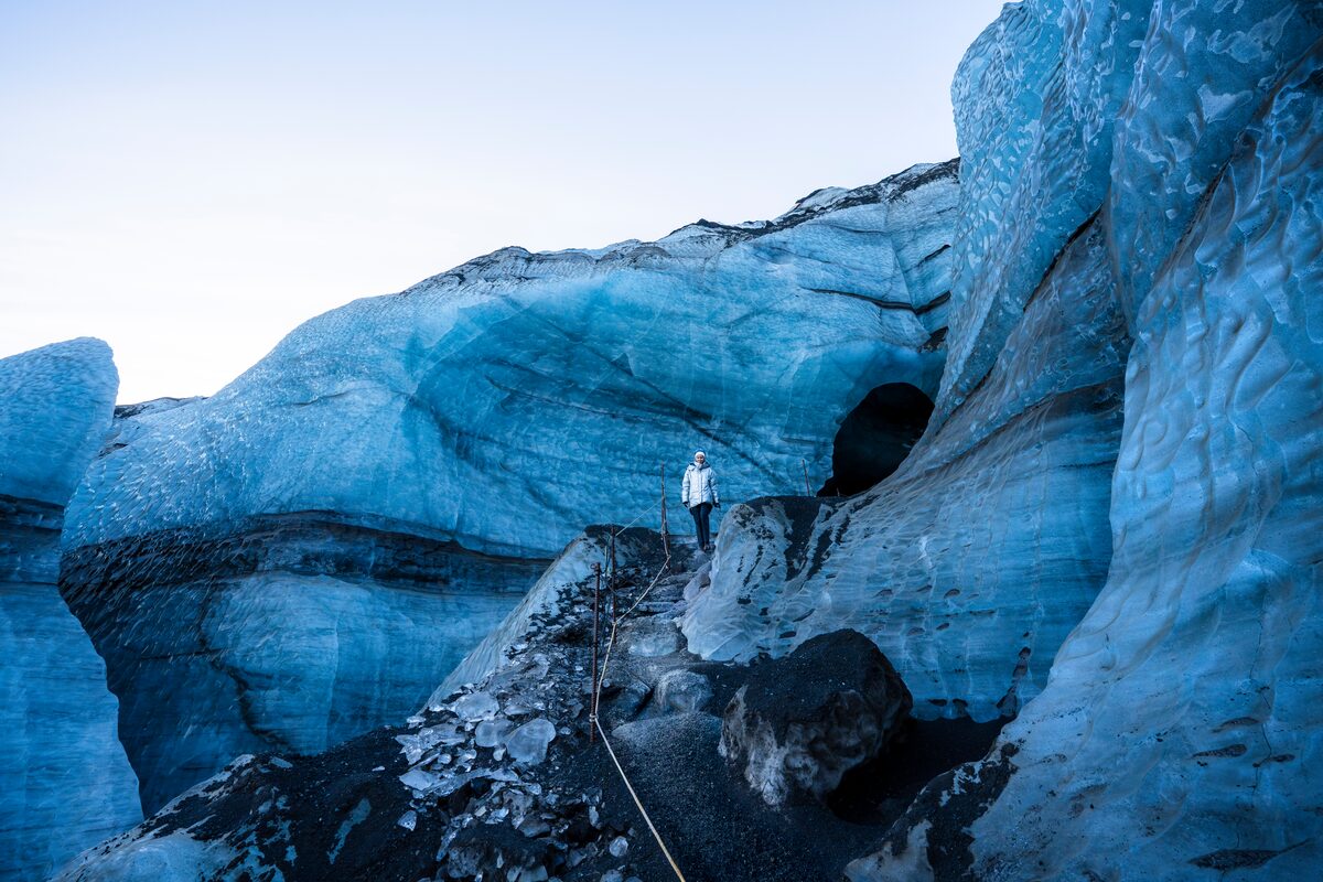 Female tourist walking on blue Kotlujokull glacier outlet close to Katla ice cave entrance.