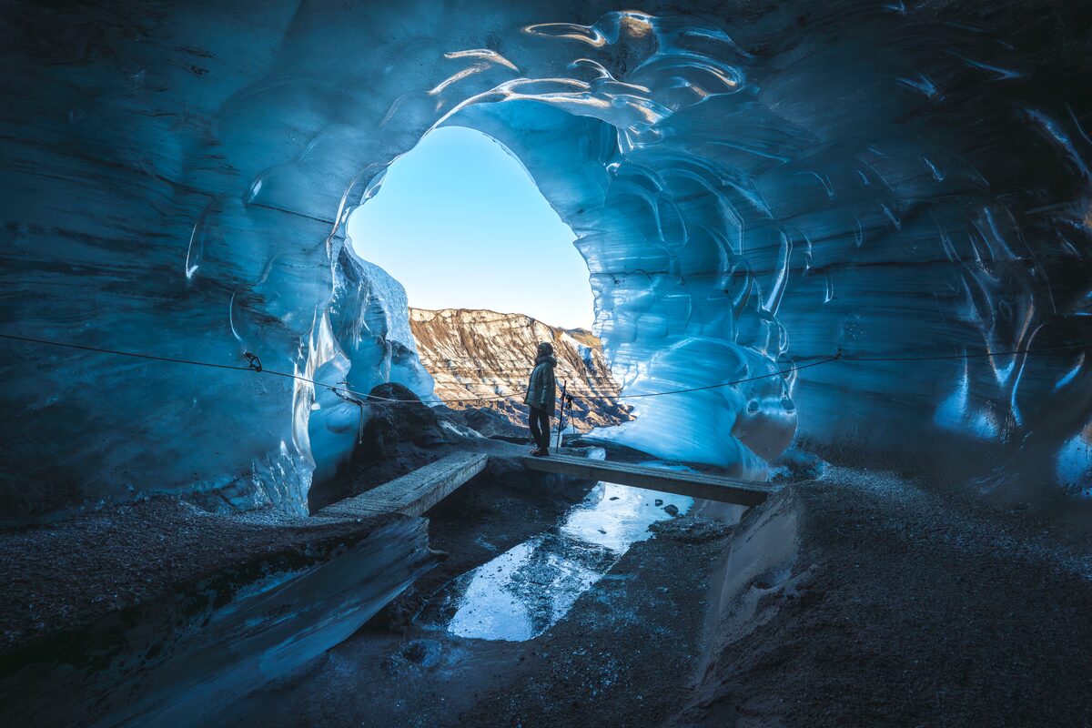 Female tourist inside Katla ice cave entrance during winter time.