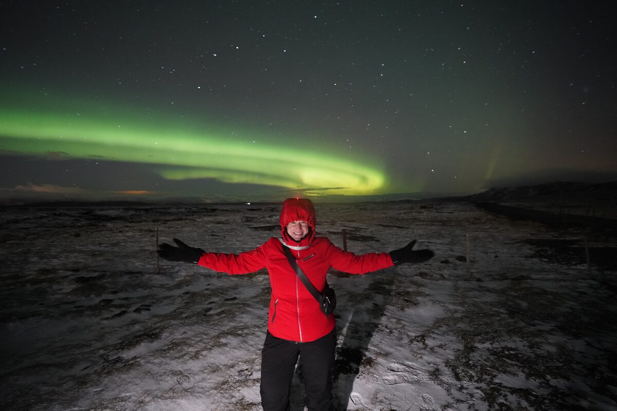 Woman With Her Arms Spread Under Norther Lights in iceland