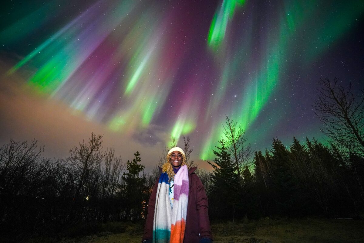 Woman In A Colorful Scarf Posing Under Nortehrn Lights in iceland