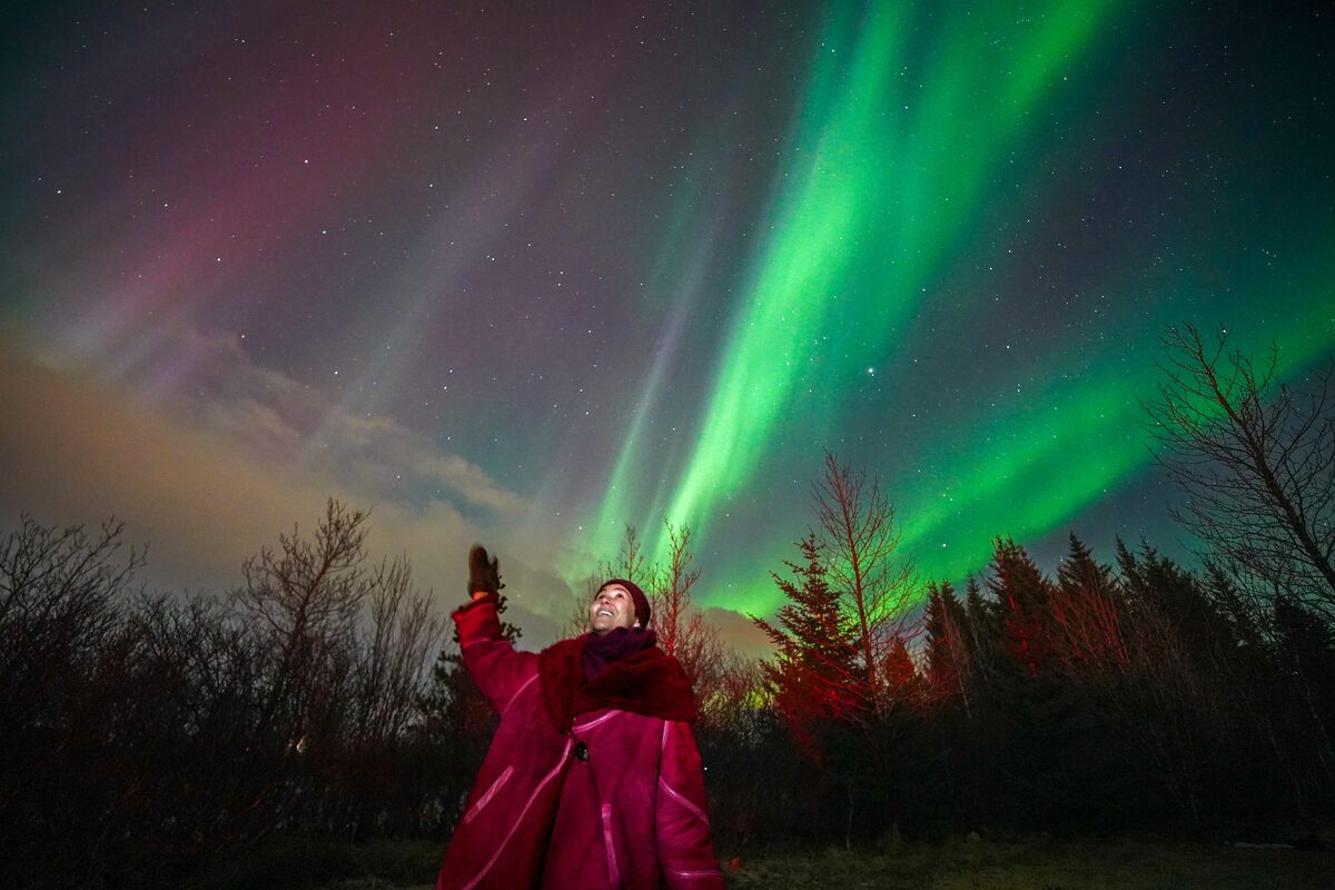 Woman Looking Up At The Sky Filled With Northern Lights in iceland