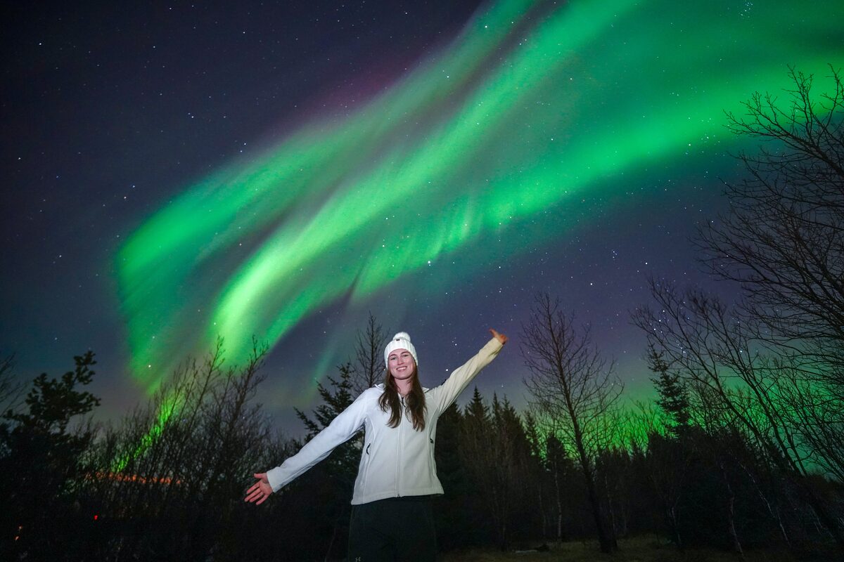 Woman Spreading Her Arms Under Northern Lights in iceland