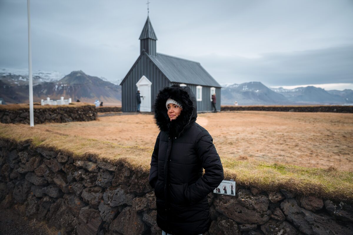 Woman In A Black Coat In Front Of A Black Church in iceland