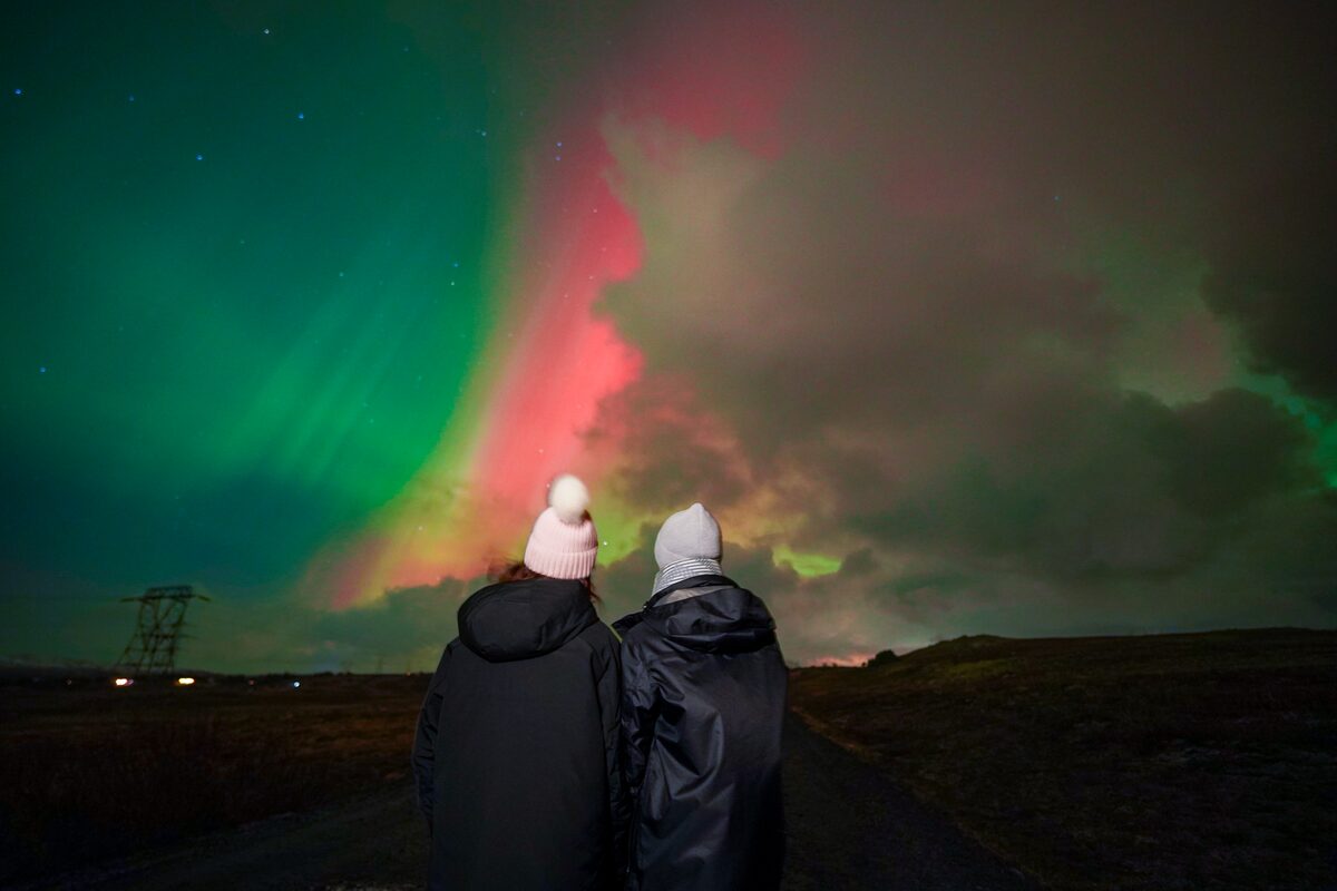 couple of friends posing underneath the northern lights at night in Iceland