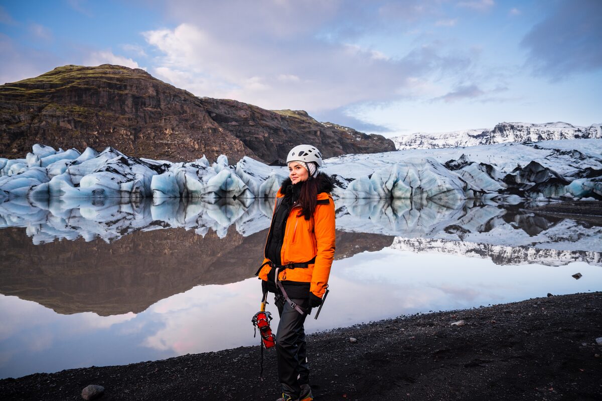 Woman In Orange Jacket Near Glacier In Iceland