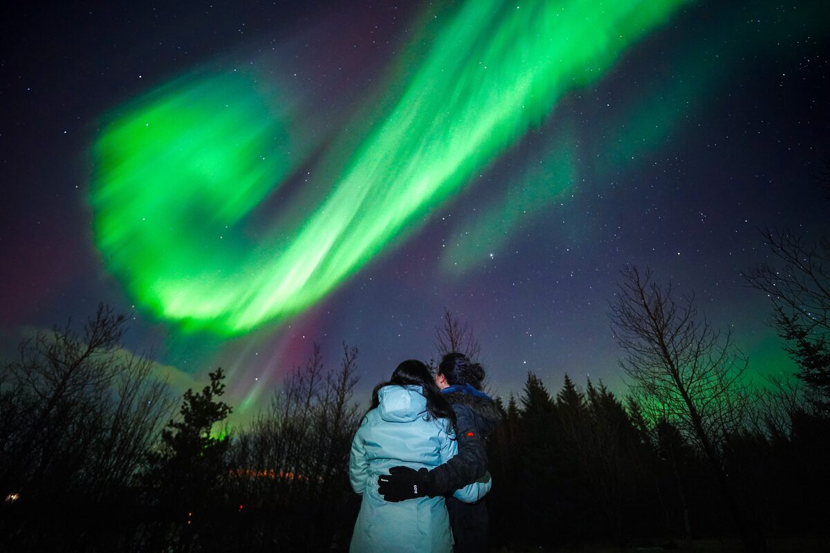 Couple Mesmerised By The Dance Of Northern Lights in iceland
