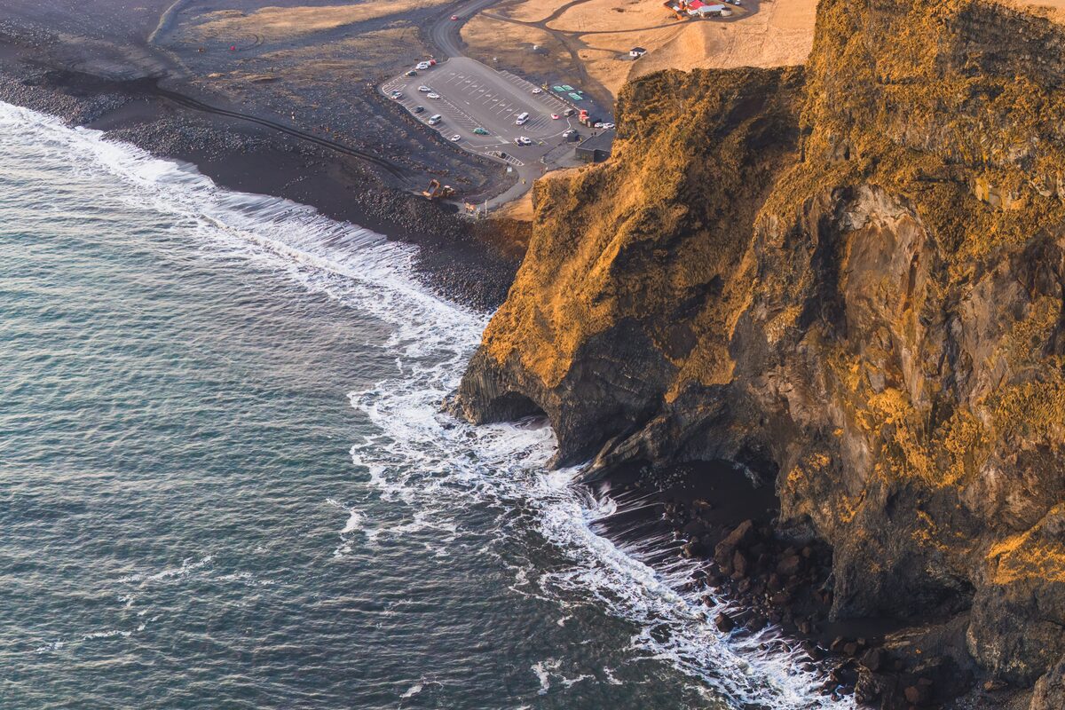 Wide view of Reynisfjara black sand beach with basalt columns and dramatic Atlantic waves in South Iceland. 