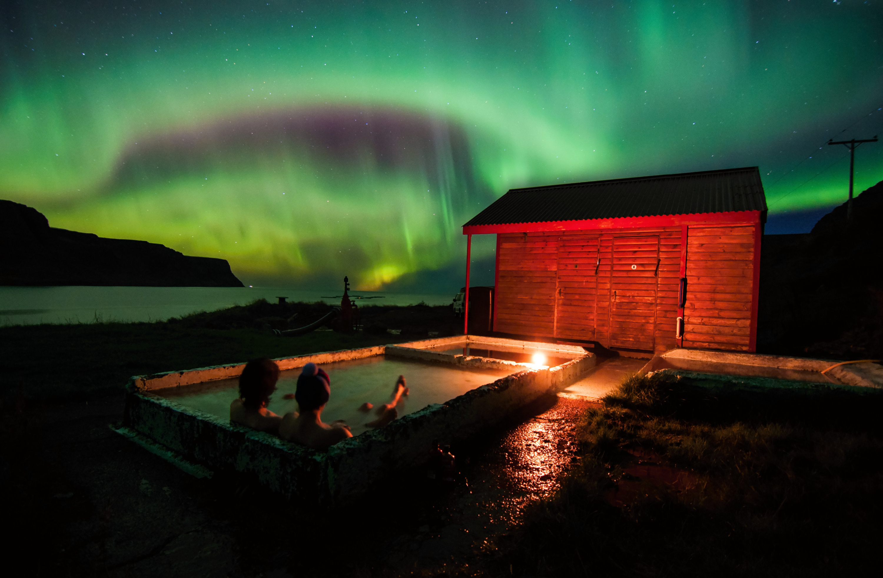 Northern Lights over a geothermal hot spring on a clear winter night in Iceland.
