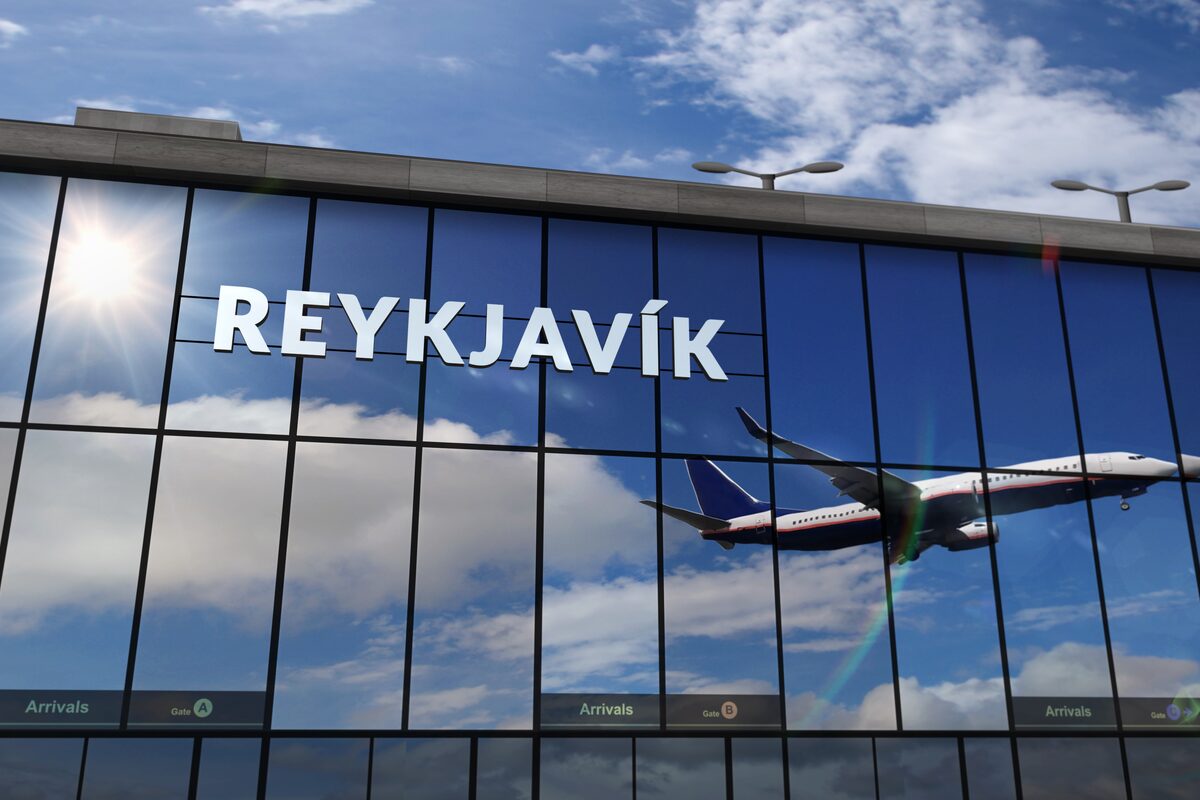 Glass airport building and an airplane reflected in the windows.