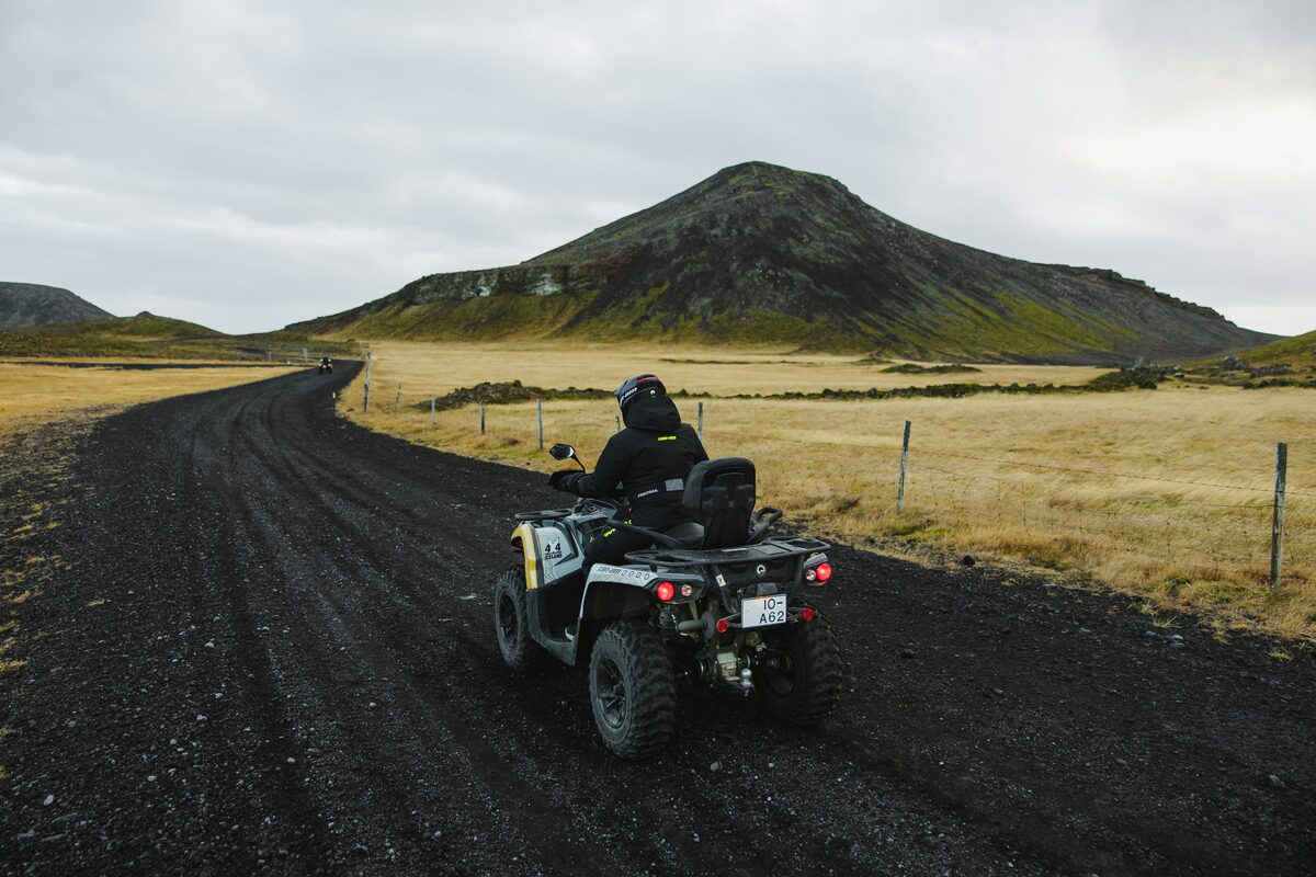 The Back Of A Person On An Atv On Black Dirt Road in Iceland