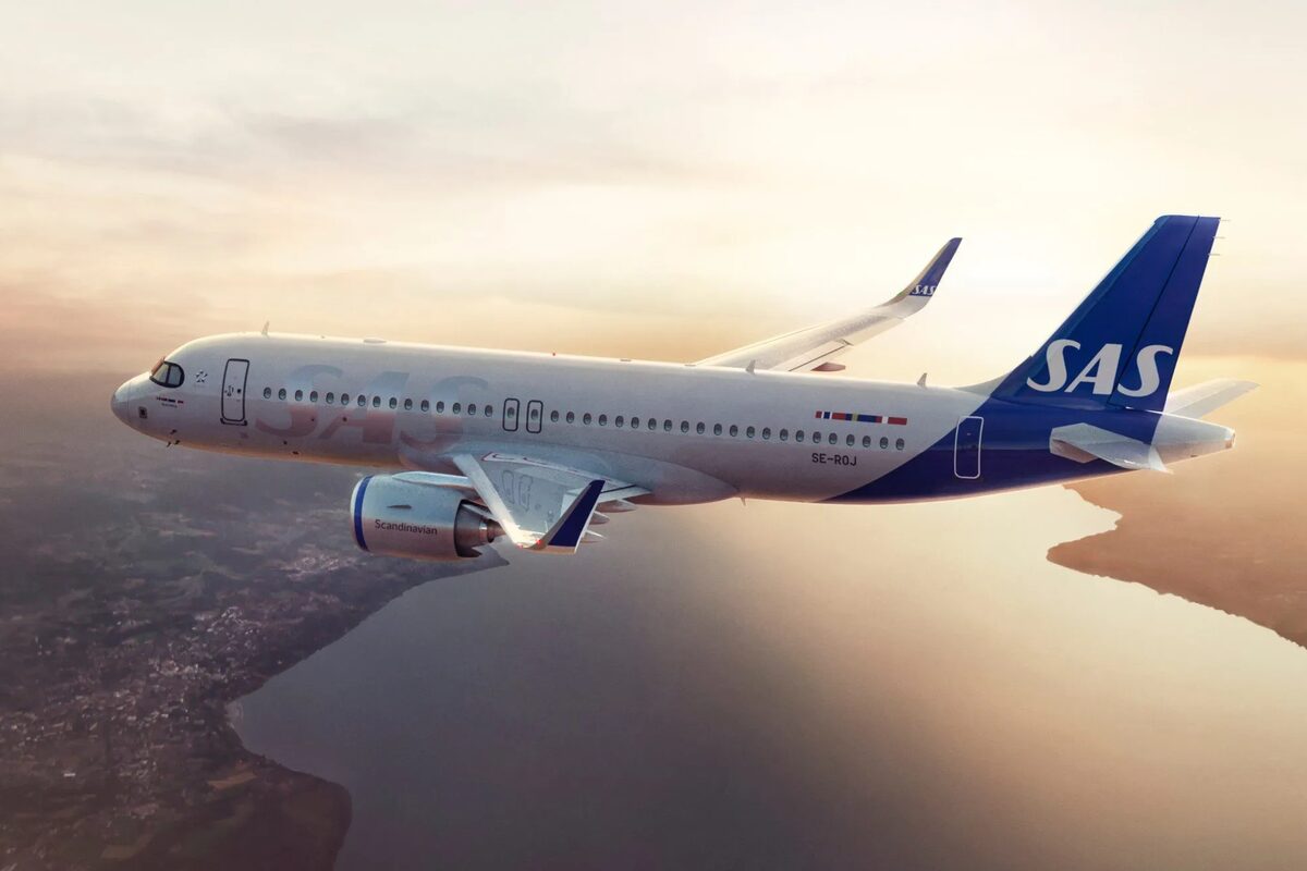 SAS airplane flying over a coastline at sunset.