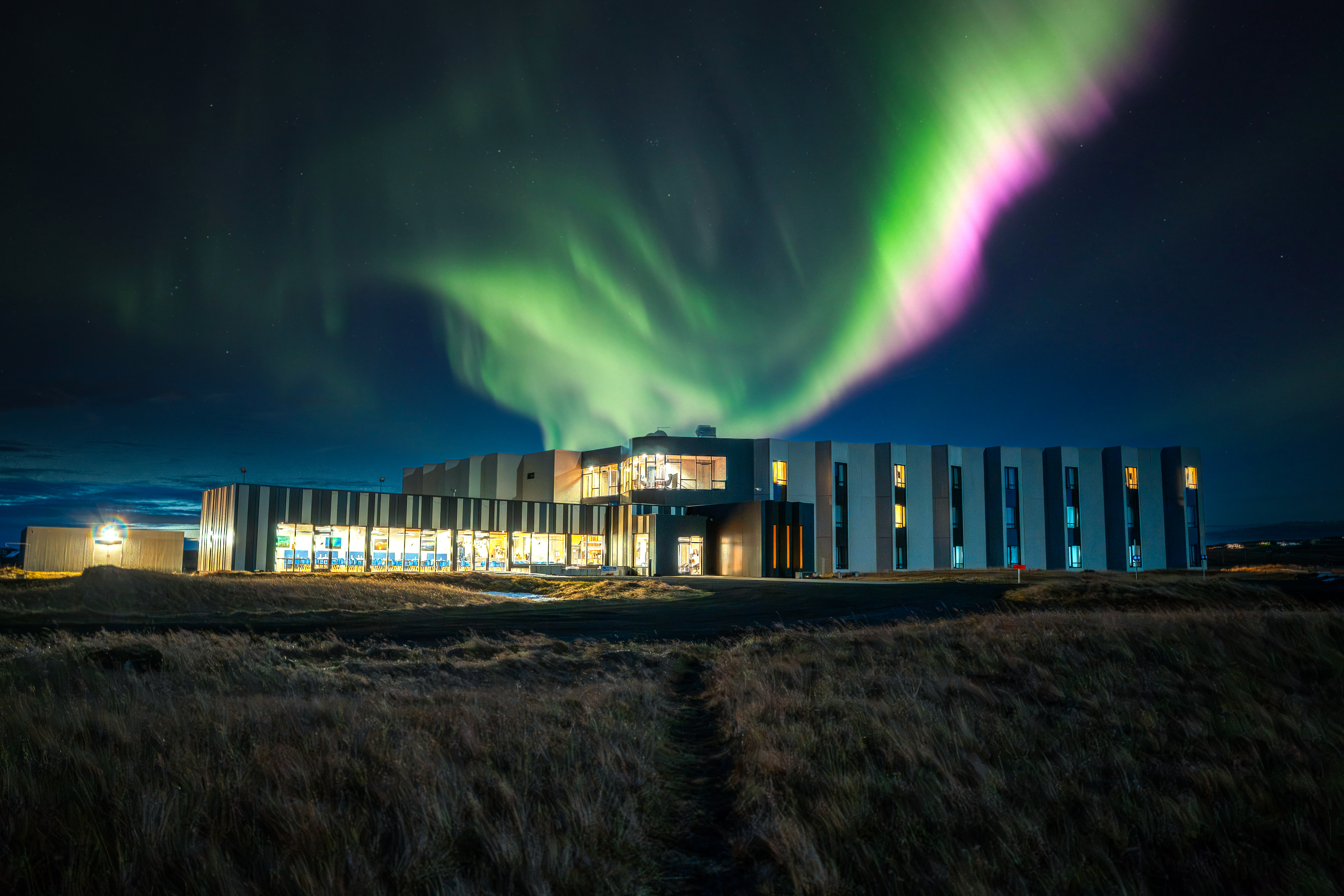 Bright green and pink Northern Lights above Landhotel in South Iceland at night.