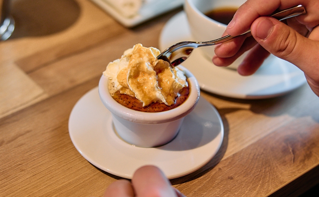 Spoonful of whipped cream lifted from a small brown dessert dish on a café table.