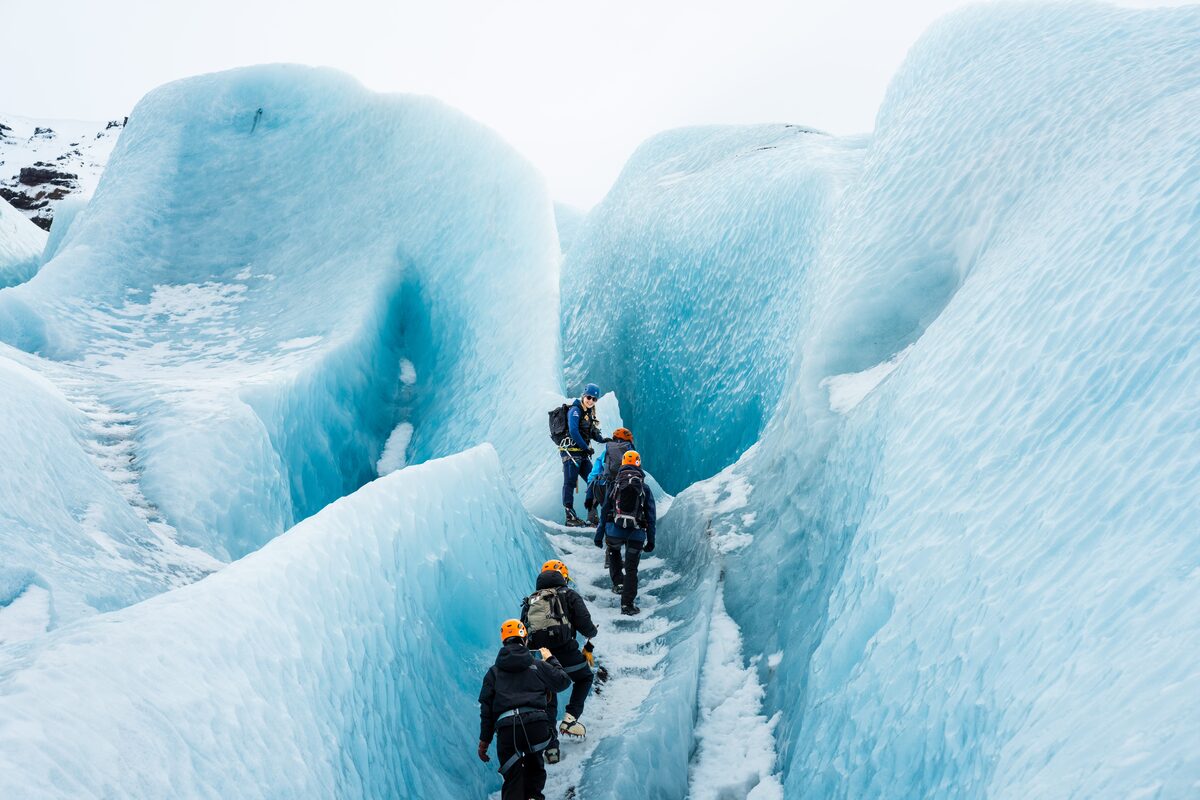 Friendly guide leading guests up blue ice staircase surrounded by blue ice walls