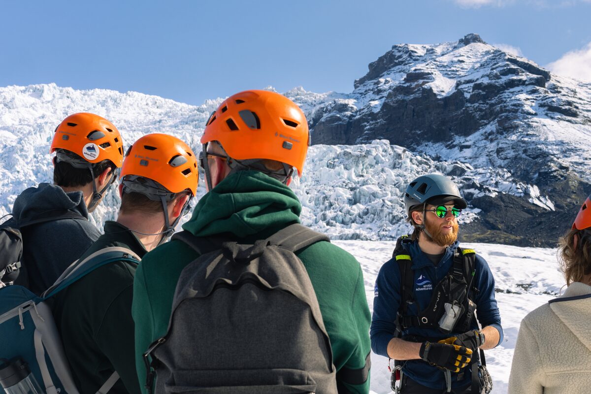 Guide talking to small group of guests in orange helmets