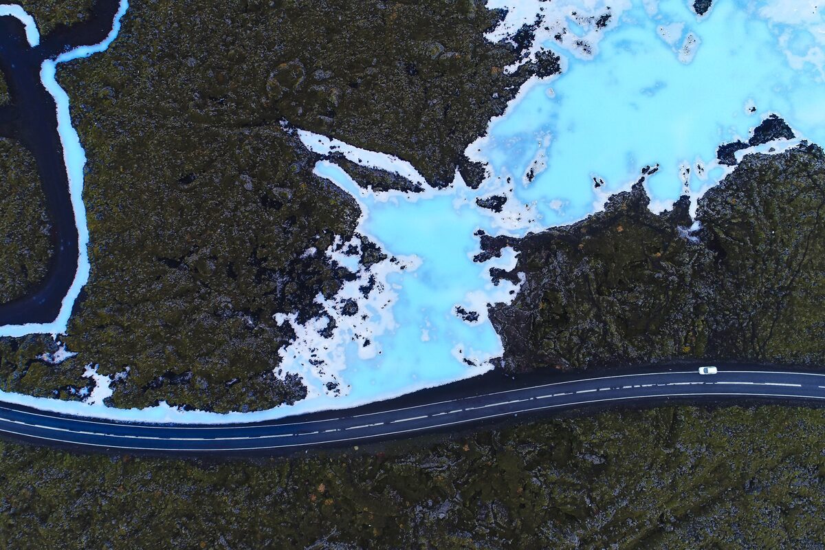 Aerial view of the Blue Lagoon area with milky blue water, lava fields, and a road nearby in Iceland.