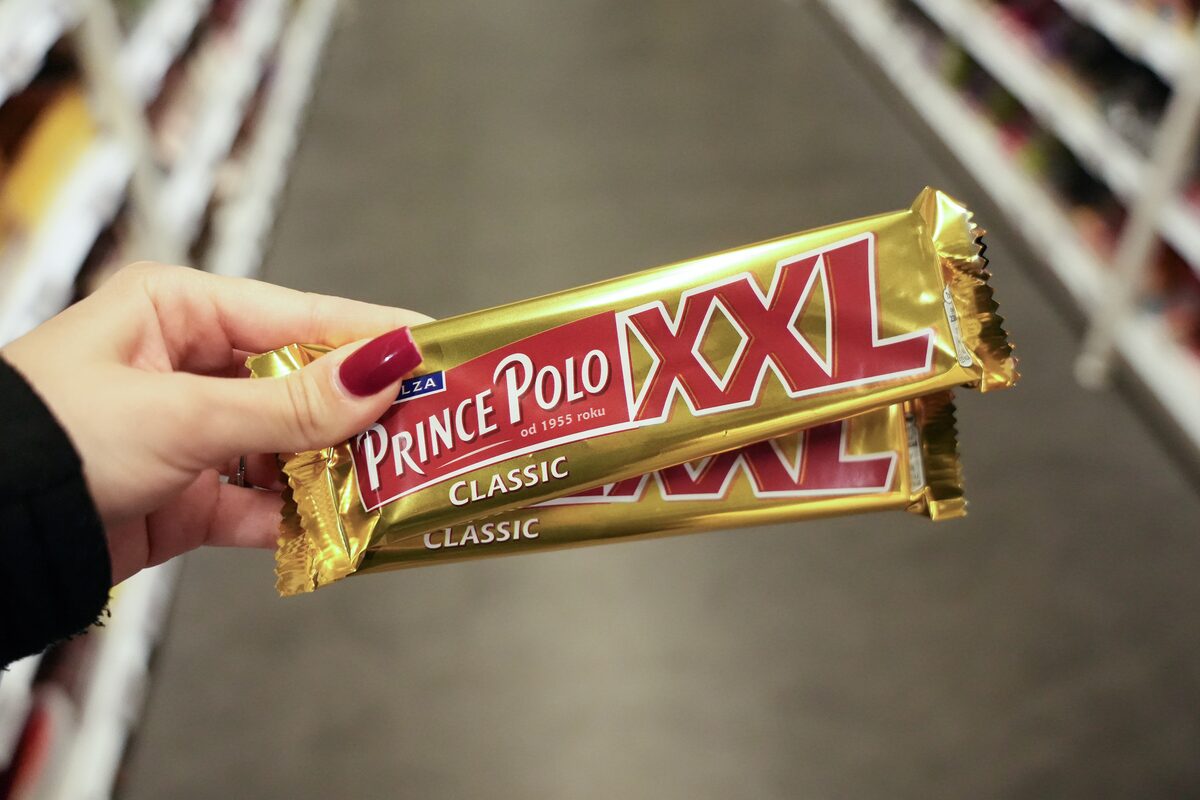 Hand holding a Prince Polo XXL Classic chocolate wafer bar in a store aisle.