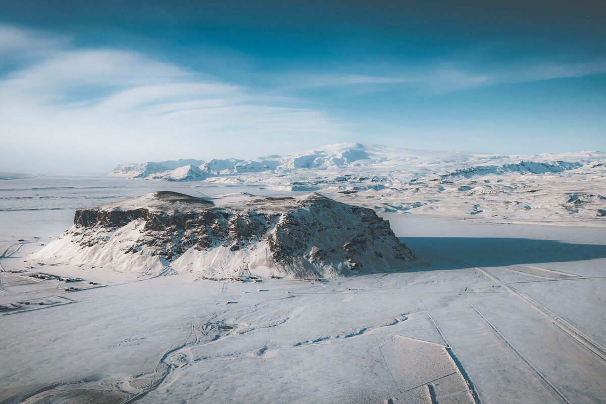 Snow-covered Eyjafjallajökull volcano and ice cap seen from above with the flat south Iceland coastal plain below.