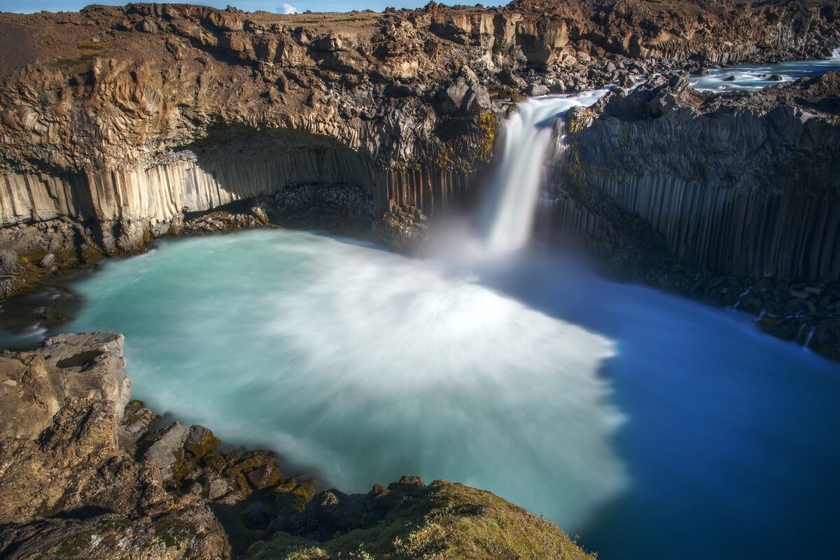 Aldeyjarfoss waterfall dropping into a turquoise pool surrounded by dark basalt columns.