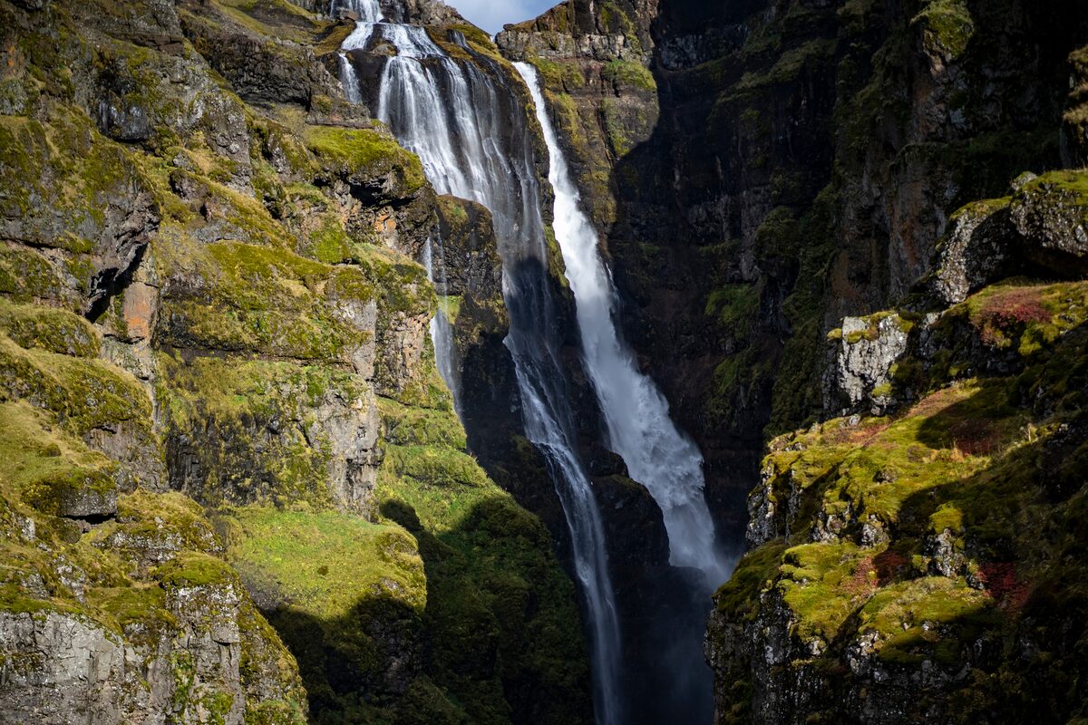 Glymur waterfall falling into a steep mossy canyon in Botnsdalur valley.