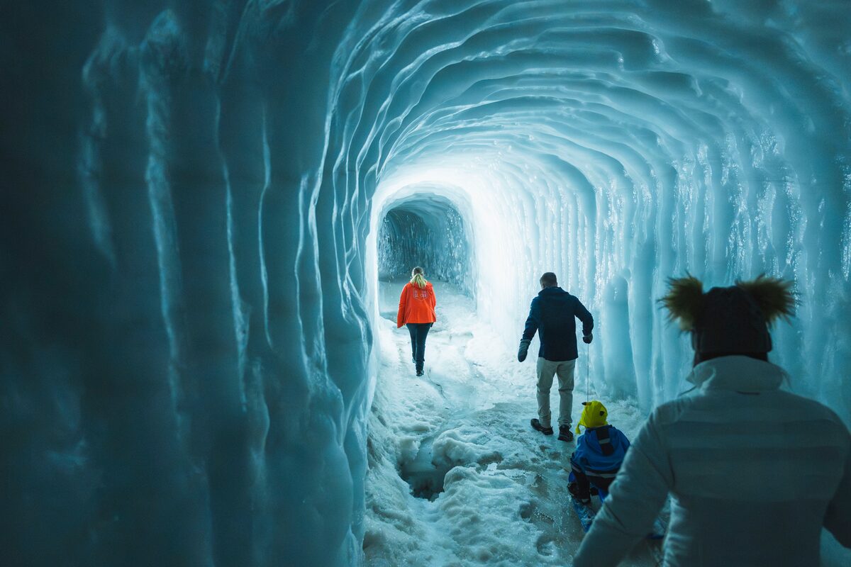 Adults and a child walking through an ice tunnel inside Langjökull glacier in Iceland.